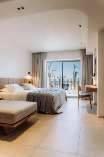 a hotel room with two beds and a balcony at Ostria Resort & Spa in Ierapetra