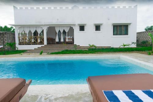 a villa with a swimming pool in front of a house at Villa Clarida in Watamu