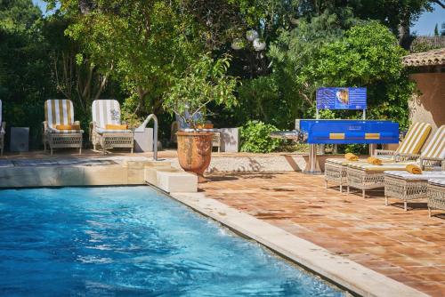 - une piscine avec des chaises et une table de ping-pong dans l'établissement La Ferme D'Augustin, à Saint-Tropez