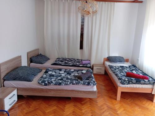 two beds in a room with wooden floors at Vila Nina 