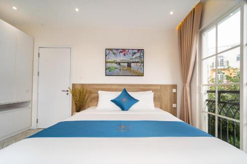 a bedroom with a blue and white bed and a window at Novus Sol Hotel & Apartment Sunset Town Phu Quoc in Phu Quoc