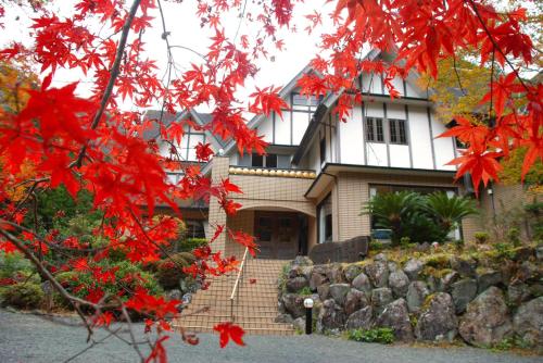 a house with red leaves in front of it at 風香る森のホテル鈴桃rindou in Shizuoka