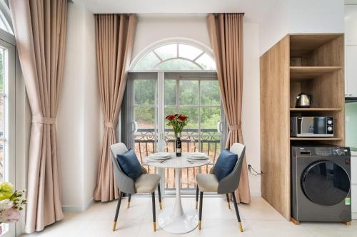 a dining room with a table and chairs in front of a window at Novus Sol Hotel & Apartment Sunset Town Phu Quoc in Phu Quoc