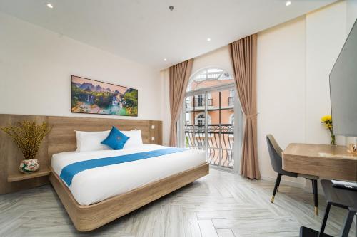 a bedroom with a bed and a desk and a window at Novus Sol Hotel & Apartment Sunset Town Phu Quoc in Phu Quoc