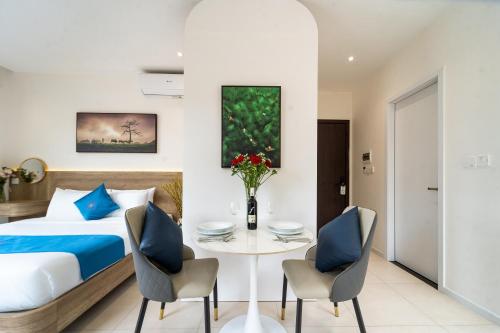a bedroom with a bed and a table and chairs at Novus Sol Hotel & Apartment Sunset Town Phu Quoc in Phu Quoc