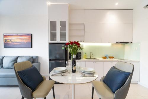 a white kitchen with a white table and chairs at Novus Sol Hotel & Apartment Sunset Town Phu Quoc in Phu Quoc