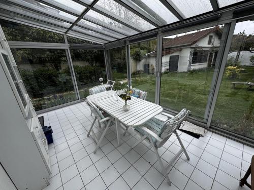 une table blanche et des chaises sur un patio grillagé dans l'établissement Le calme entre Paris et Disney, à Villiers-sur-Marne