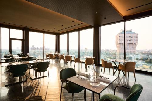 a restaurant with tables and chairs and large windows at Uptown Palace in Milan