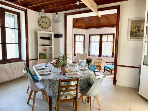 a dining room with a table with chairs and a clock at Les Lutins Villa Le Pouliguen in Le Pouliguen