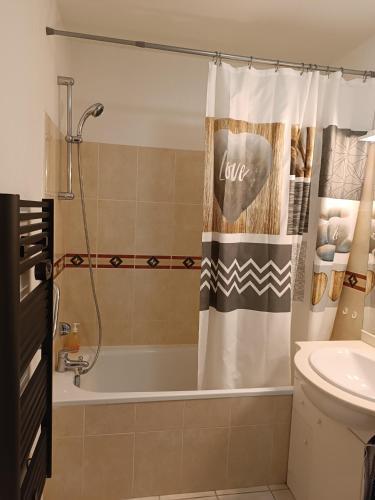 La salle de bains est pourvue d'une baignoire et d'un rideau de douche. dans l'établissement Entre Terre et Mer, à Villeneuve-lès-Béziers