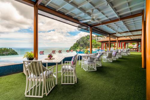 a row of white chairs and tables with the ocean in the background at Ayara Kamala Resort & Spa - SHA Extra Plus in Kamala Beach