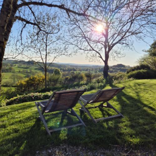 deux chaises assises dans l'herbe avec le soleil en arrière-plan dans l'établissement Le Mas de Rigoulac 5 Chambres d'hotes & SPA sur réservation table d hôtes sauf les mercredis et les dimanches, à Bouyssounouse
