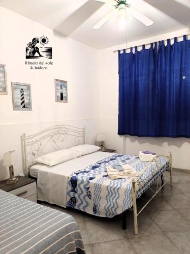 Un dormitorio con dos camas y una cortina azul. en Il bacio del sole - S. Isidoro, en Sant'Isidoro