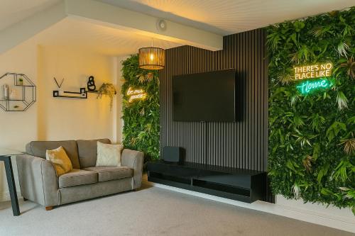 a living room with a couch and a tv on a wall at Nestee Serviced Apartments - Central Torquay - Pet Friendly - Harbour Views in Torquay