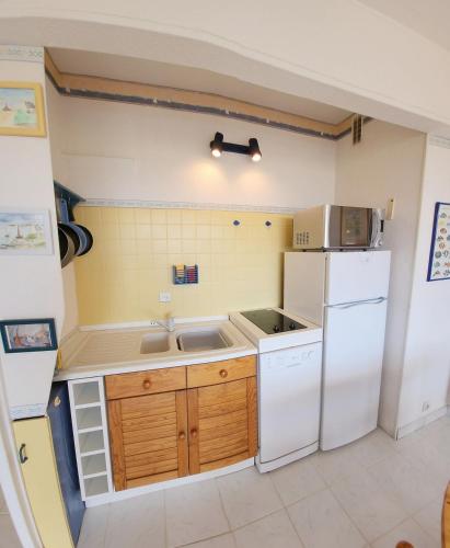 une cuisine avec un réfrigérateur blanc et un évier dans l'établissement T2 Le Saule Perché, 5p, beach 500m, terrace, park, à Fréjus
