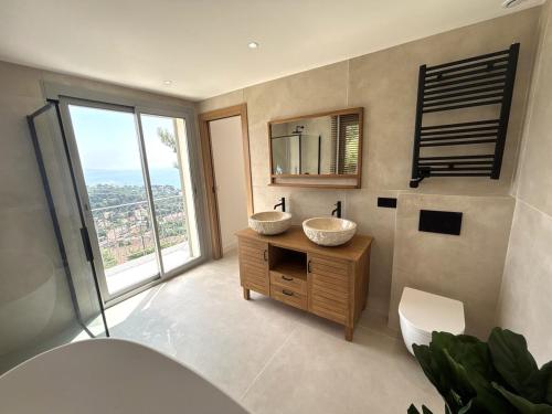 La salle de bains est pourvue de 2 lavabos et d'une grande fenêtre. dans l'établissement Villa Roca sea view, à Roquebrune-Cap-Martin