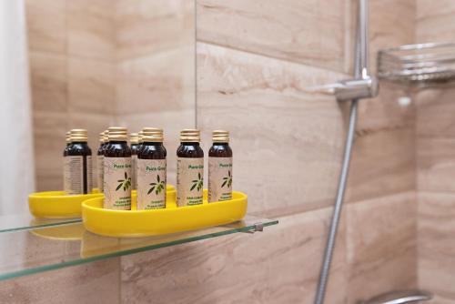 four bottles of beer sitting on a glass shelf in a shower at Nest Green Apartment Varna in Varna City