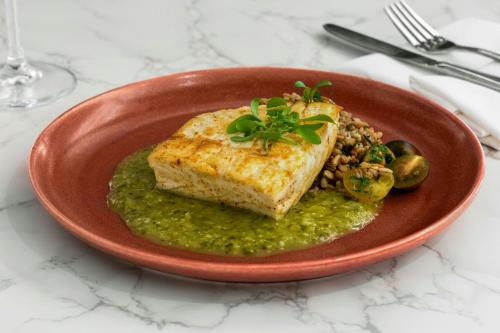 a red plate with a piece of fish with green sauce at Sheraton Universal in Los Angeles