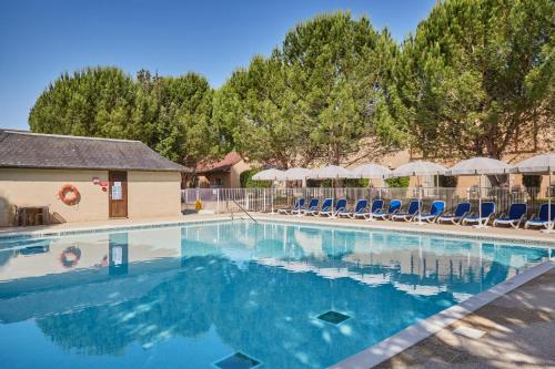 une grande piscine avec chaises et parasols dans l'établissement Résidence Odalys Le Hameau du Moulin, à Montignac