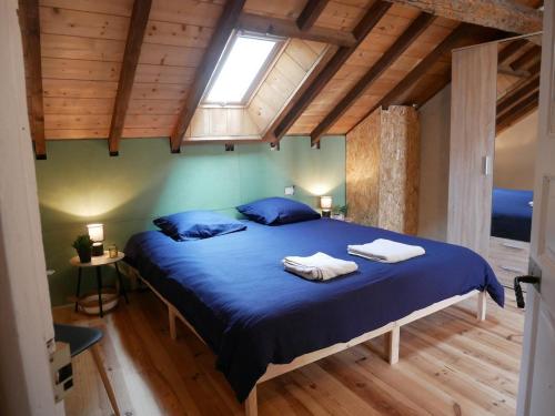 a bedroom with a bed with blue sheets and a window at La Maison Arola in Bagnères-de-Bigorre