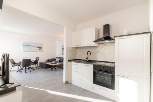 a kitchen with white cabinets and a living room at Villa Valamare in Podstrana