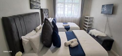 Una sala de estar con dos camas con almohadas azules y blancas. en Khaya Apartments Victoria Falls Estate, en Victoria Falls