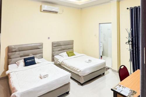a room with two beds and a table and a mirror at Urbanview Botania Meeting Point Batam by RedDoorz in Nongsa