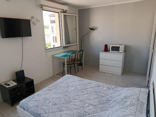 - une chambre avec un lit, une table et un four micro-ondes dans l'établissement Studio proche centre ville, à Avignon