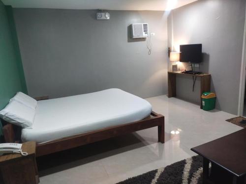 a small bedroom with a bed and a television at Hope Pension House - Danao in Danao City