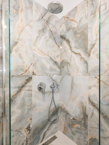 a bathroom with a shower with marble walls at SeaWave Villas, By Hellocrete in Chania Town