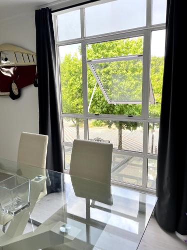 a glass table and chairs in front of a large window at Apartamento Portus Apostoli in Noya