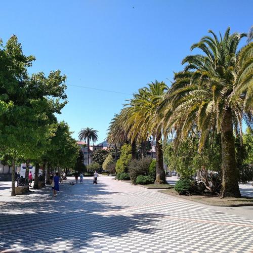 a sidewalk with palm trees and people walking down it at Apartamento Portus Apostoli in Noya