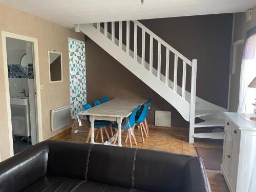 un salon avec une table et des chaises bleues dans l'établissement Maison pieds dans l'eau Caroual, à Erquy