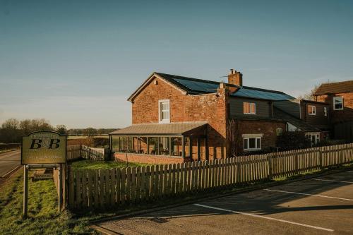 a brick house with a fence next to a road at Crossroads House in Carlisle