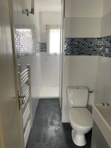 une salle de bain blanche avec toilettes et fenêtre dans l'établissement Maison pieds dans l'eau Caroual, à Erquy