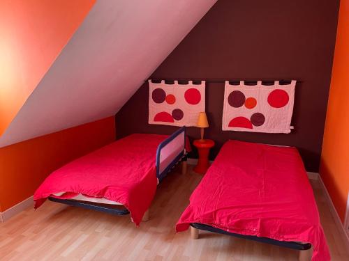 - 2 lits dans une chambre aux murs rouge et orange dans l'établissement Maison pieds dans l'eau Caroual, à Erquy