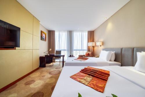 a hotel room with two beds and a flat screen tv at Huzhou Changxing New Zijin Hotel in Huzhou