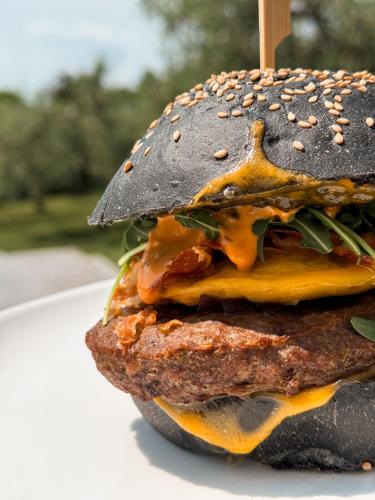 a hamburger with cheese and vegetables on a plate at La Cipressina B&B in Cavaion Veronese