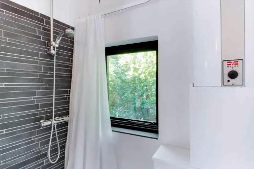 a bathroom with a shower curtain and a window at Peaceful Beach House Life Just 50 M From Shore in Dronningmølle