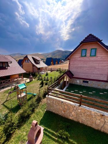 a house with a stone wall in a field at Starry Sky Zlatibor in Krajevi