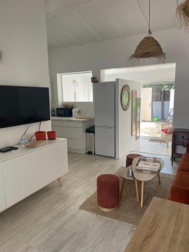 un salon blanc avec une télévision et une table dans l'établissement L'escapade, à Saint-Tropez