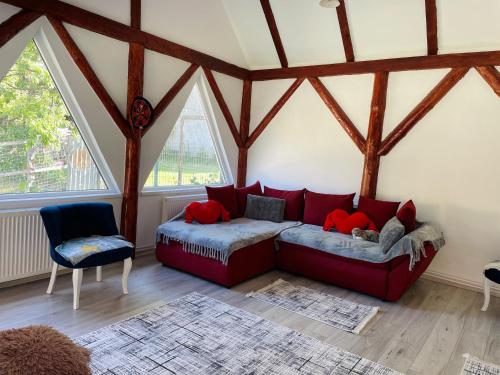 a living room with a red couch in a room with windows at Casa Din Lunca in Poiana Mărului