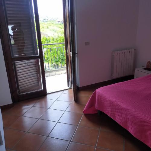 a bedroom with a bed and a door with a balcony at aranceto dell'Etna in Mascali