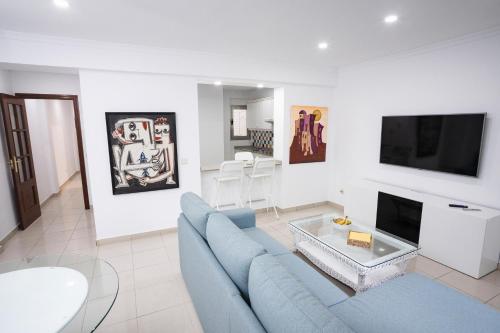 un salon avec un canapé bleu et une télévision dans l'établissement Coral Canteras Playa - Frente al mar - Ideal parejas, familias o trabajo, à Las Palmas de Gran Canaria