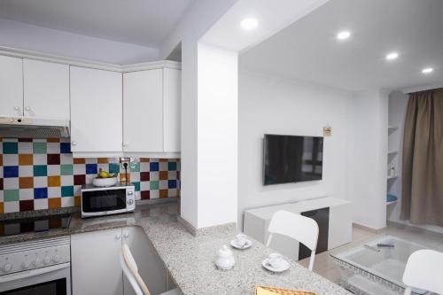 une cuisine avec des armoires blanches et un comptoir dans l'établissement Coral Canteras Playa - Frente al mar - Ideal parejas, familias o trabajo, à Las Palmas de Gran Canaria