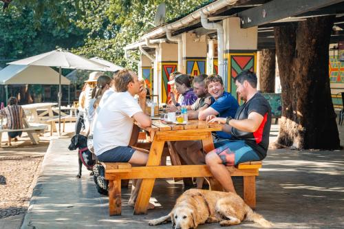 a group of people sitting at a table with a dog at Shoestrings Backpackers Lodge Vic Falls in Victoria Falls