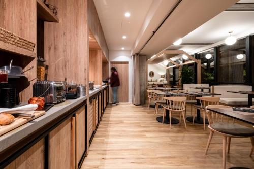 une personne debout dans un restaurant avec des tables et des chaises dans l'établissement Mercure Grenoble Centre Alpotel, à Grenoble