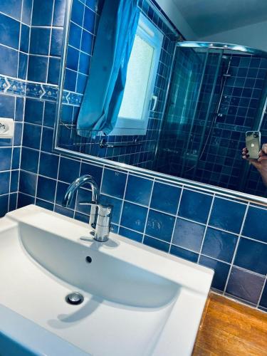 La salle de bains est pourvue de carrelage bleu, d'un lavabo et d'un miroir. dans l'établissement Charme de la côte d'azur, à Aigue-Belle