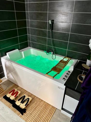 a bath tub filled with blue water in a bathroom at Sakura Suite - Jacuzzi and Cinema in Saint-Quentin
