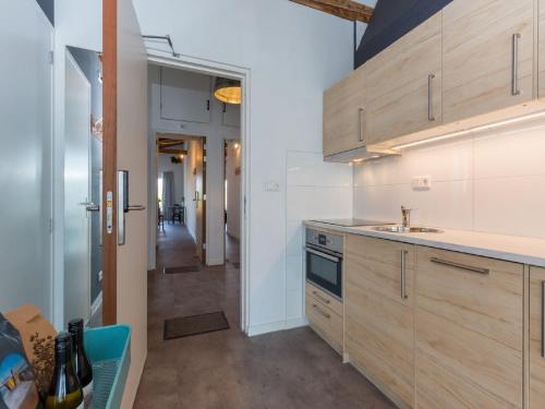 a kitchen with wooden cabinets and a sink and a hallway at Lovely, modern, 4-person apartment in the heart of Koudekerke in Koudekerke
